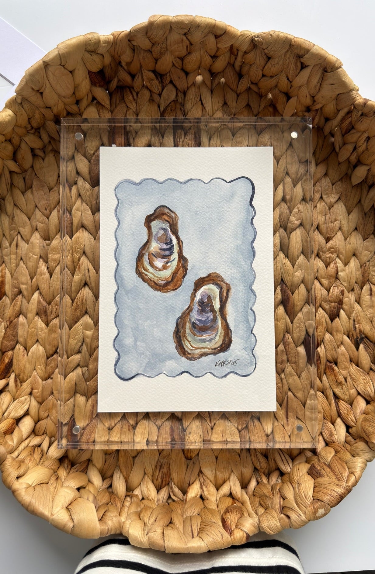 Woven basket with a card featuring two oyster shells on a white surface