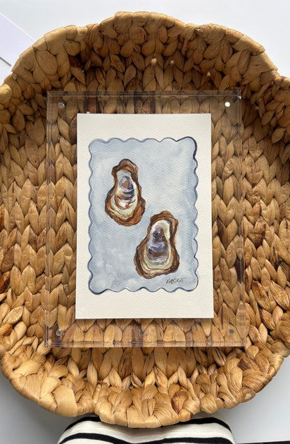 Woven basket with a card featuring two oyster shells on a white surface