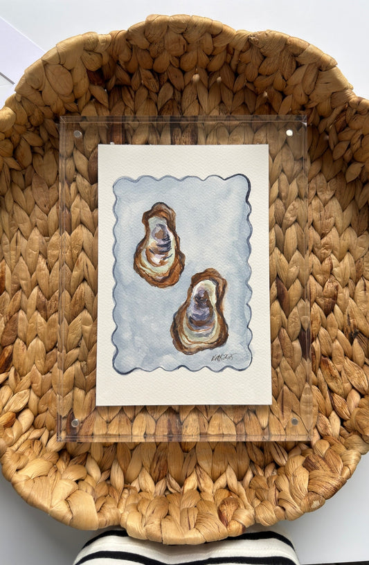 Woven basket with a card featuring two oyster shells on a white surface